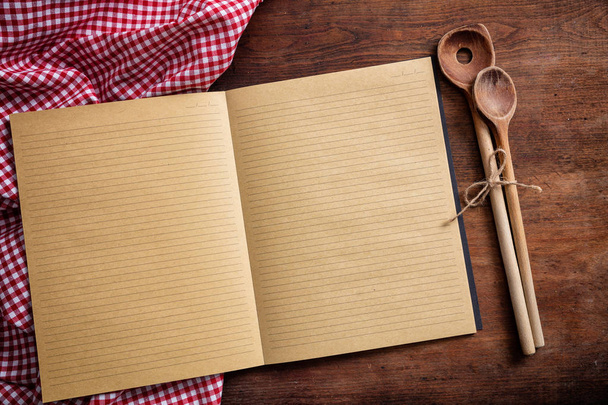 Cooking recipe. Blank notebook, kitchen utensils and red tablecloth on wooden table, top view, copy space - Photo, Image