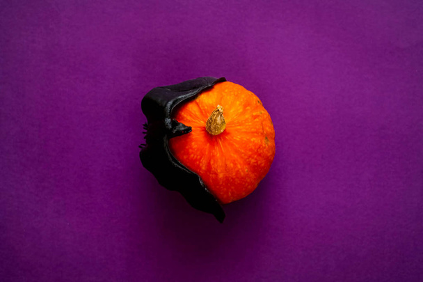 Символ HALLOWEEN оранжевая тыква и летучая мышь изолированы на фиолетовом фоне
 - Фото, изображение