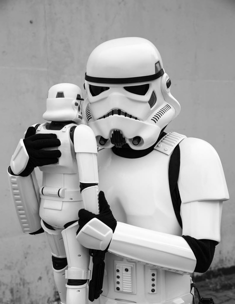SHEFFIELD, Reino Unido - 18 de agosto de 2018. Un cosplayer masculino vestido como un Stormtrooper de Star Wars abrazando a su hijo que está vestido con un traje de Stormtrooper de juguete en un retrato de padre e hijo en un evento cómico con una estafa
 - Foto, Imagen