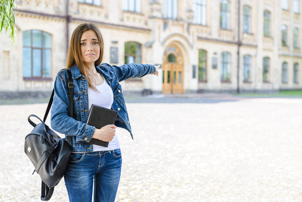 I do not want to go back to school! Help! Photo portrait of sad upset frustrated depressed shy awkward horrified attractive cute pretty girl showing on doors to classroom blurred autumn background - 写真・画像