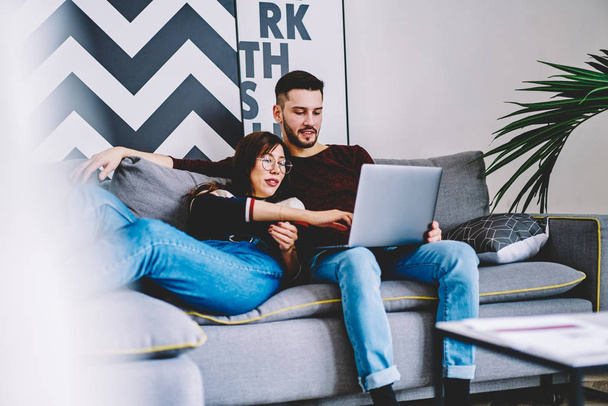 Couple in love resting together on sofa and choosing website with movie online on modern laptop device using wireless internet.Marriage booking tickets on website spending leisure time at home - Fotó, kép