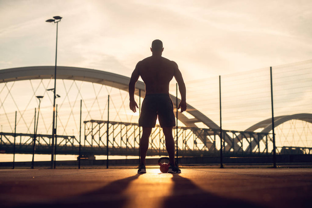 Fitness edzés a szabadban. Sziluettjét jóképű férfi kora reggel a napkelte - Fotó, kép