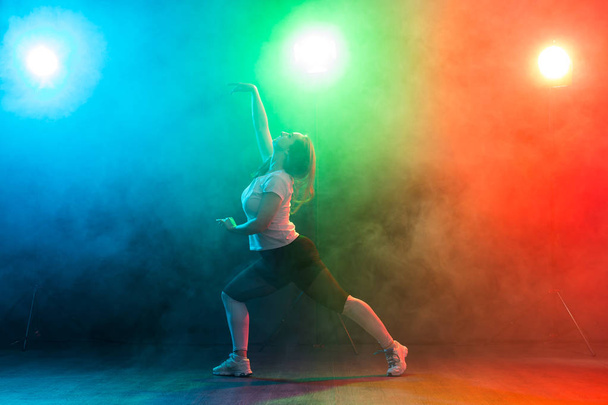 Menschen, Tanz und Jazz-Funk-Konzept - Europäische junge Frau demonstriert Flexibilität über farbigen Hintergrund - Foto, Bild