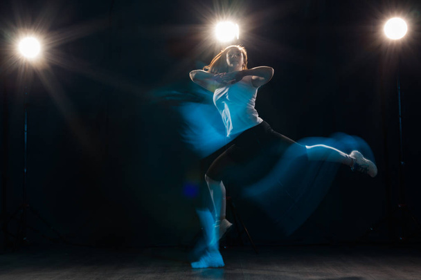 Танцы, спорт, красивая и народная концепция - молодая женщина, танцующая в темноте, прыгала в ярком свете
 - Фото, изображение