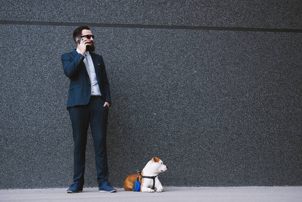 Businessman walking dog at street. Best friends walking. Handsome businessman hipster walking dog. - Foto, Imagen