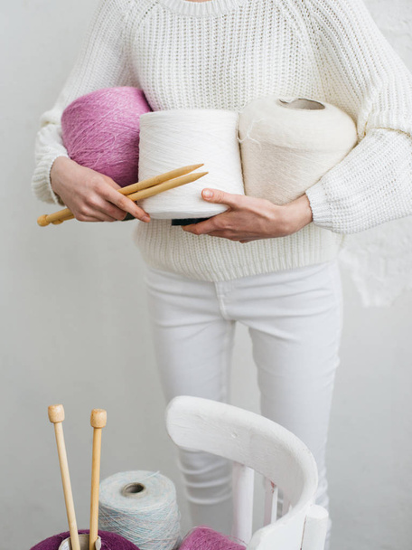 Pretty young woman knits woolen clothes. Girl with knitting needles and wool yarn - Фото, зображення