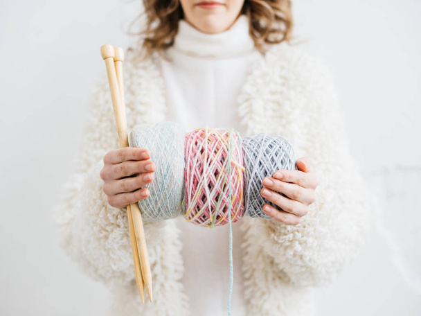 Closeup of pretty young woman in white woolen clothes with knitting needles and wool yarn - Foto, Bild