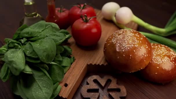 Video zeigt Zutaten für leckere Burger, frisches Gemüse und Gemüse zum Kochen, Semmeln mit Sesam, Burger kochen, Fastfood-Rezepte, Kochen zu Hause - Filmmaterial, Video