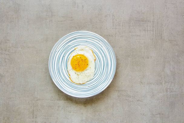 Breakfast fried egg in plate on light stone background flat lay. Food. Breakfast. Healthy food. Top view - Фото, изображение
