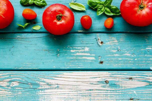 Fresh tomato and basil leaves on wood flat lay. - Foto, afbeelding