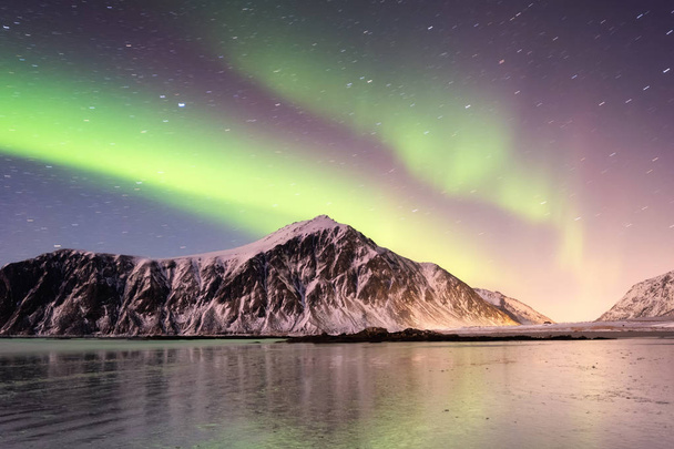 Nordlichter auf den Lofoten, Norwegen. grüne Nordlichter über den Bergen. Nachthimmel mit Polarlichtern. Nachtwinterlandschaft mit Polarlichtern und Spiegelungen auf der Wasseroberfläche. Natürlicher Hintergrund in Norwegen - Foto, Bild