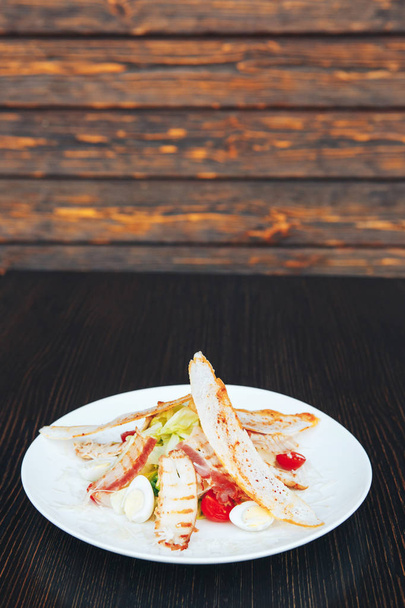 Ensalada César con pollo y verduras sobre mesa de madera. Placa con ensalada de pollo en la mesa
 - Foto, imagen