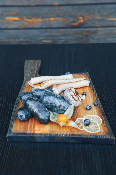 Grilled fried black sausages on a wooden board. Black sausages on the grill - Photo, Image