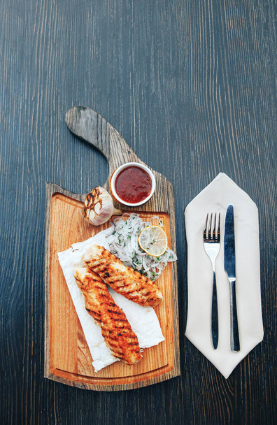 Carne de kebab a la parrilla con cebolla y salsa en una tabla de madera
 - Foto, imagen
