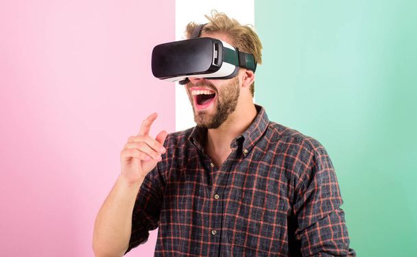 Hipster use modern technologies for entertainment. Guy with VR glasses or head mounted display. Interaction in virtual reality with digital surface. Man unshaven guy with VR glasses, pink background - Photo, image
