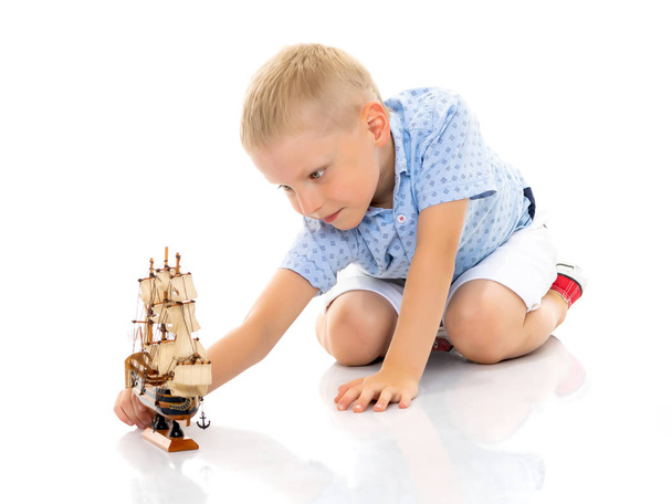 A little boy is playing with a boat. - Foto, Bild