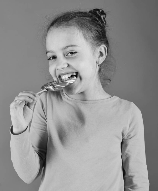 Girl eats big colorful caramel. Lady holds round shaped lollipop. - Foto, Imagen