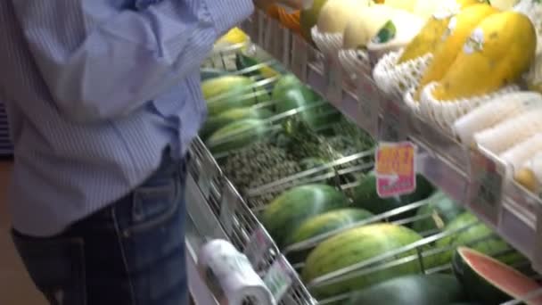 Nainen valita Melon, joka on sijoitettu hyllylle supermarketissa
. - Materiaali, video