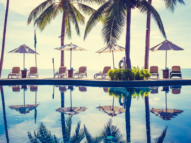 Sombrilla y silla alrededor de una lujosa piscina al aire libre en hotel y resort para vacaciones y viajes
 - Foto, Imagen
