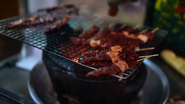 Grilled pork on a spit, night market in Banlung town. Woman slice piece of meat from one big piece of pig which hanging on the roast.    - Séquence, vidéo
