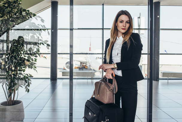 Beautiful airhostess standing in her uniform with her bags ready for a flight - 写真・画像