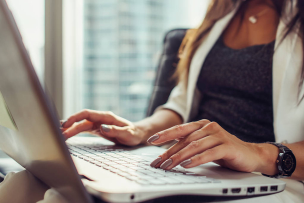 Zbliżenie dłoni na klawiatura kobieta przy użyciu netbook siedzi w biurze - Zdjęcie, obraz