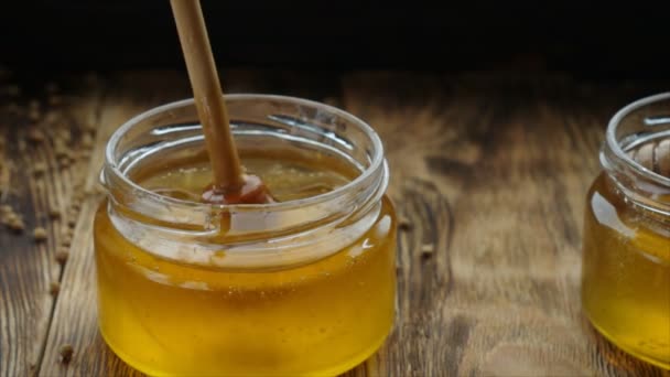 Mel em um frasco de vidro com um conta-gotas de mel de madeira em uma mesa de madeira
 - Filmagem, Vídeo