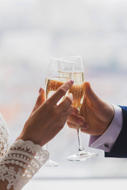 Man en vrouw handen met twee champagneglazen, versierd met bloemen voor de ceremonie van het huwelijk - Foto, afbeelding