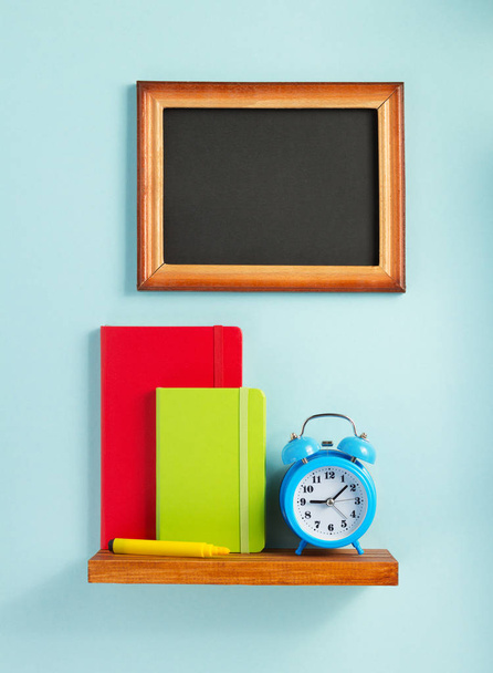 notepad and alarm clock on shelf at wall background surface - Fotografie, Obrázek