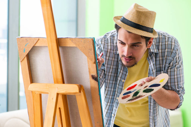 Fiatal férfi művész dolgozik az új festmény a stúdióban - Fotó, kép