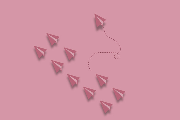 Minimal drawing business concept for different thinking and team leader for group paper plane point to one destination and another one paper plane point to another destination with pink background - Foto, afbeelding
