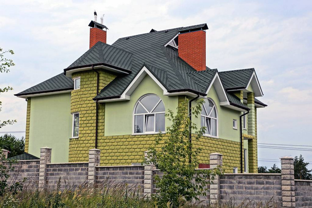 grande casa verde dietro una recinzione di mattoni grigi nell'erba
 - Foto, immagini