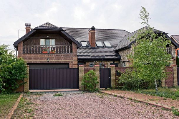 паркан і коричневі ворота металу вирощені зеленими рослинами перед приватним будинком
 - Фото, зображення