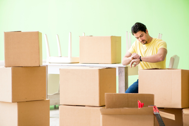 Young handsome man moving in to new house with boxes - Photo, Image