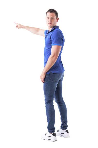Back view of young adult casual man turning and looking at camera showing directions with hand gesture. Full body isolated on white background. - Photo, Image