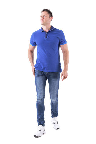 Macho young man in casual clothes walking forward and looking up. Full body isolated on white background. - Photo, Image