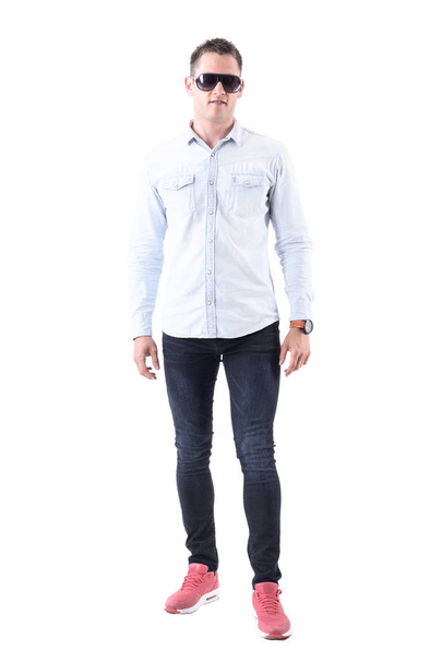 Man wearing light blue shirt, jeans and pink sneakers with sunglasses looking at camera. Full body isolated on white background. - Photo, Image