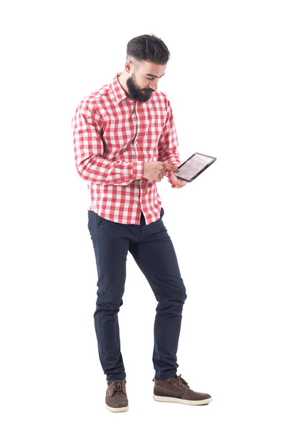 Молодий бородатий стильний бізнесмен використовує планшетний сенсорний екран з пальцем. Повна довжина ізольована на білому тлі
. - Фото, зображення