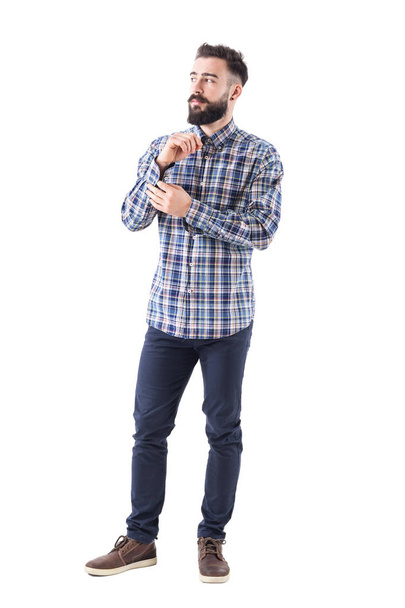 Homem barbudo macho sério confiante botão de abotoar manga ficando vestido olhando para longe. Corpo inteiro isolado em fundo branco
. - Foto, Imagem