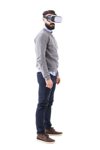 Profile view of serious bearded smart casual man using virtual reality glasses. Full body length portrait isolated on white studio background. - Photo, Image