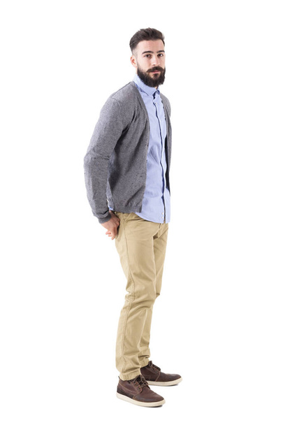 Young stylish bearded man in cardigan with hands in back pockets looking at camera. Full body length portrait isolated on white studio background. - Fotografie, Obrázek