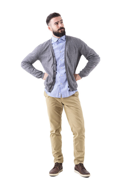 Handsome stylish bearded man thinking and looking up with arms on hips. Full body length portrait isolated on white studio background. - 写真・画像