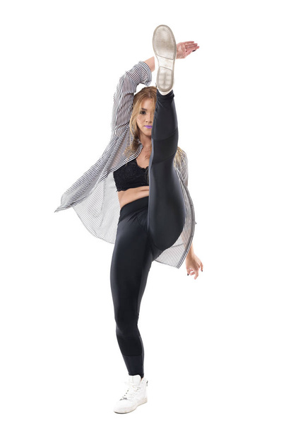 Energiczny aktywna kobieta elastyczne jazz tancerz taniec z wysokiej kick podniósł nogę. Portret długość całego ciała na białym tle na tle białego studia. - Zdjęcie, obraz