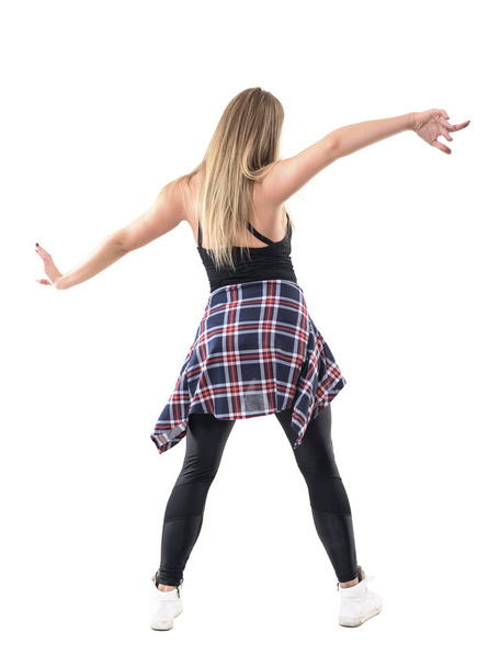 Rear view of young blonde woman dancing with outstretched spread arms posture. Full body length portrait isolated on white studio background. - Photo, Image