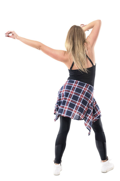 Vista posterior de una mujer apasionada bailando con una mano tocando el pelo y un brazo estirado. Retrato de cuerpo entero aislado sobre fondo blanco
. - Foto, Imagen