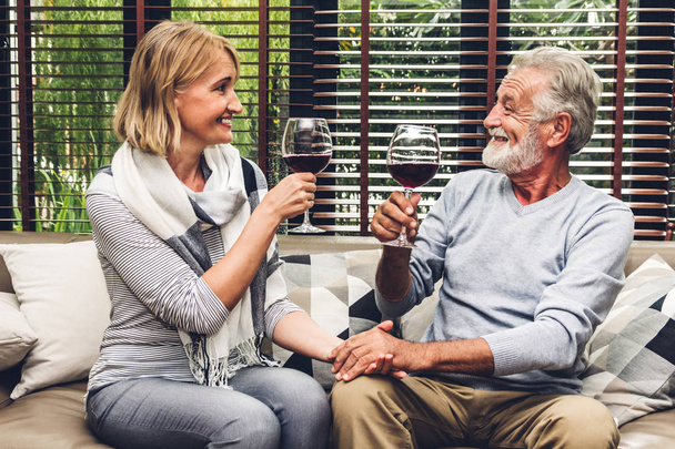 Coppia anziana rilassarsi parlando e bevendo bicchieri di vino insieme sul divano in soggiorno a casa.Pensionamento concetto di coppia - Foto, immagini