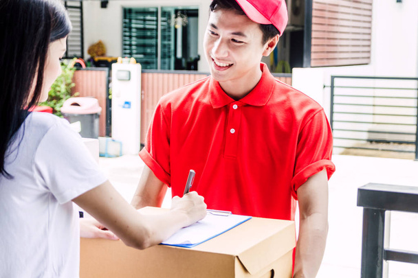 Женщина ставит подпись в буфер обмена на картонной коробке с доставкой man.courier концепции обслуживания
 - Фото, изображение