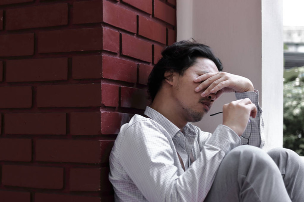 Уставший перегруженный работой молодой азиатский бизнесмен закрывает глаза и прикрывает лицо
 - Фото, изображение