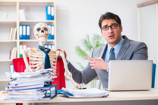 Empresario trabajando con el esqueleto en la oficina - Foto, imagen