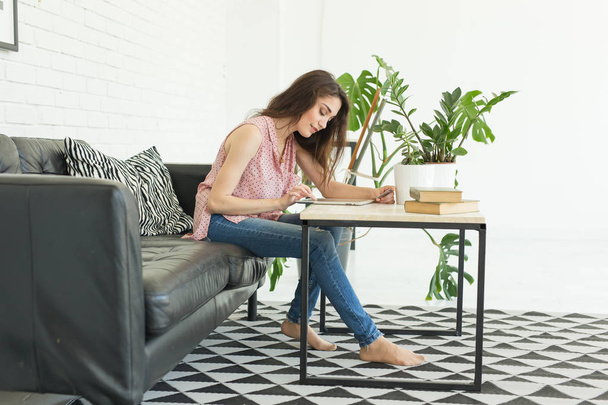 Люди, образование и концепция интерьера - молодая женщина, сидящая за столом и использующая табличку
 - Фото, изображение